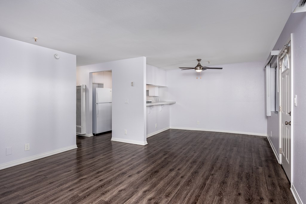 A room with a ceiling fan and wooden flooring.