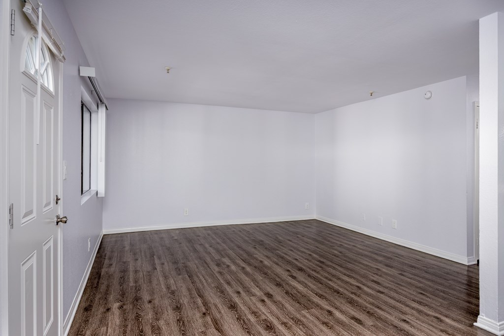 A room with wooden flooring and white walls.