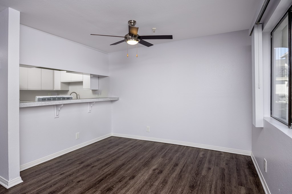 A room with a ceiling fan and wooden flooring.