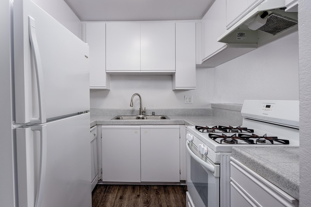 A white kitchen with a refrigerator, stove, and cabinets.