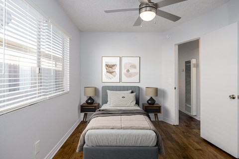 A bedroom with a bed, two lamps, and a ceiling fan.