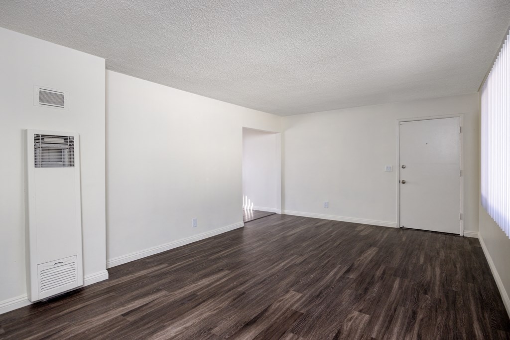 an empty living room with white walls and wood flooring