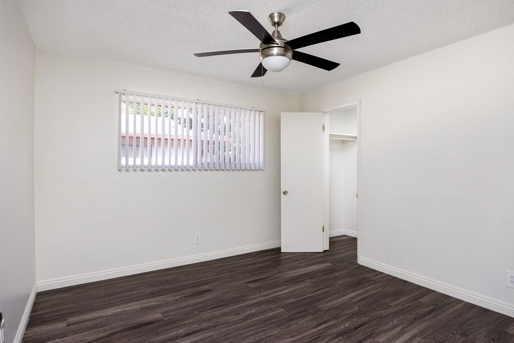 an empty living room with a ceiling fan and a window