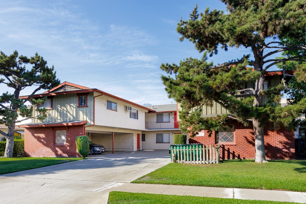 a street view of an apartment building with a white fence