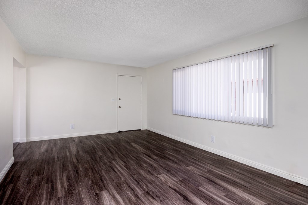 an empty living room with wood flooring and a window