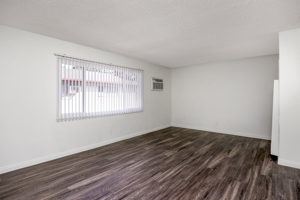 an empty living room with a window and wood flooring