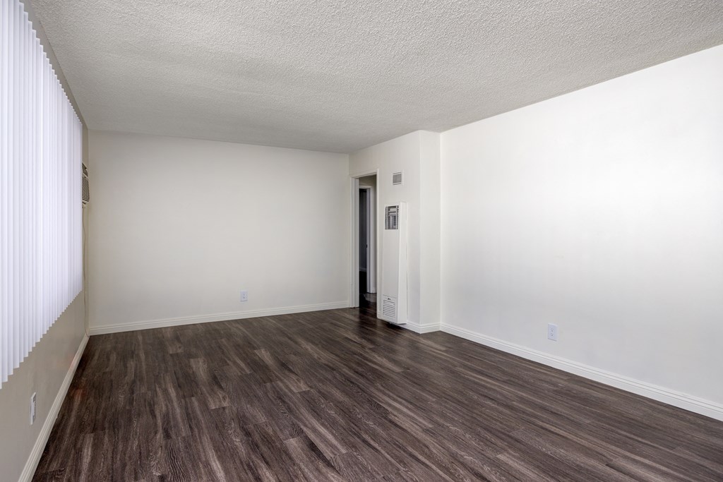 an empty living room with wood flooring and white walls