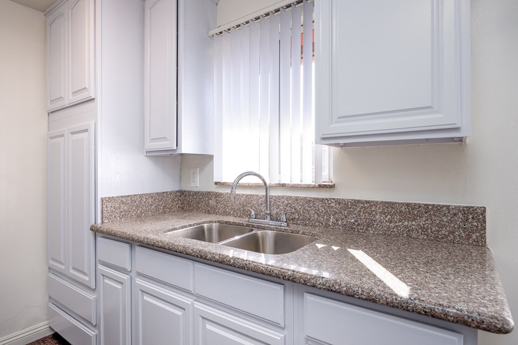 a kitchen with white cabinets and granite counter top and a sink