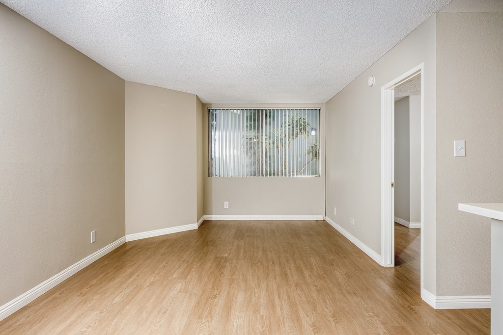 A room with wooden flooring and a window with blinds.