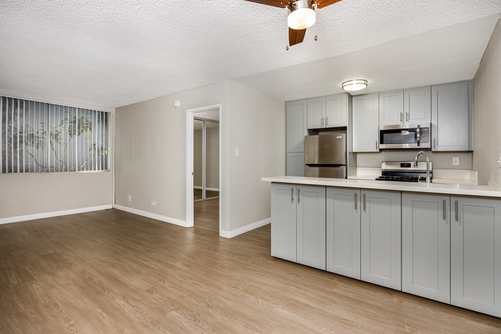 A kitchen with a fan on the ceiling and a countertop with a microwave and toaster.