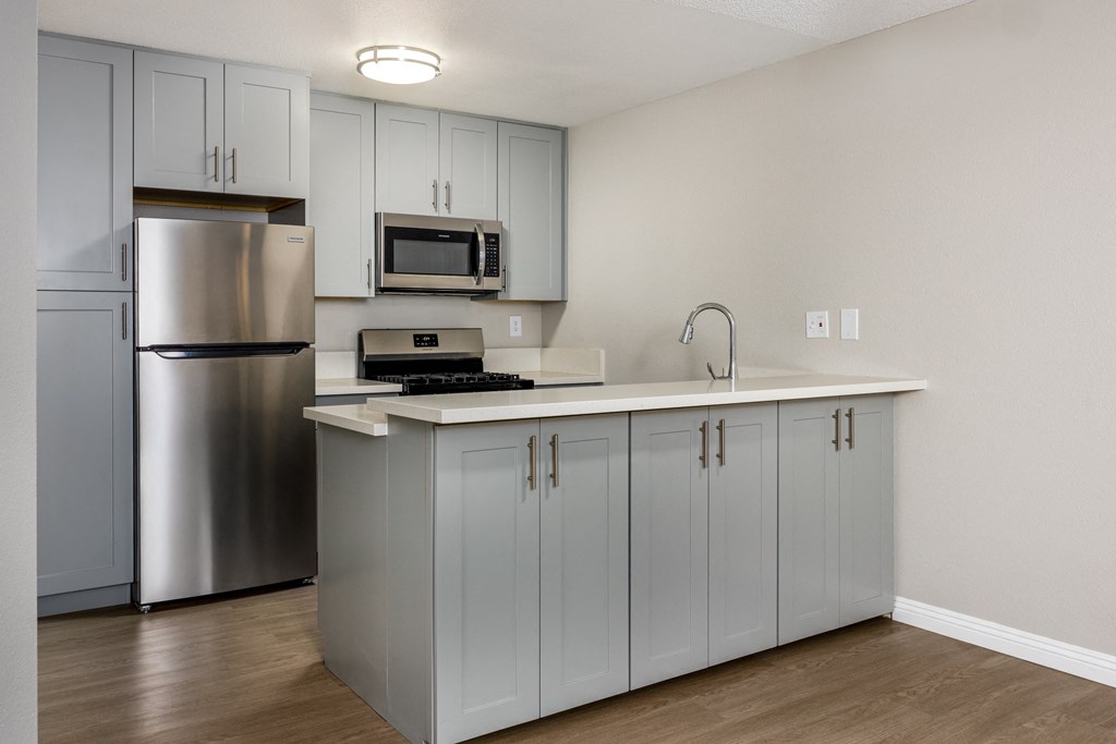 A kitchen with a stainless steel refrigerator and a white countertop.