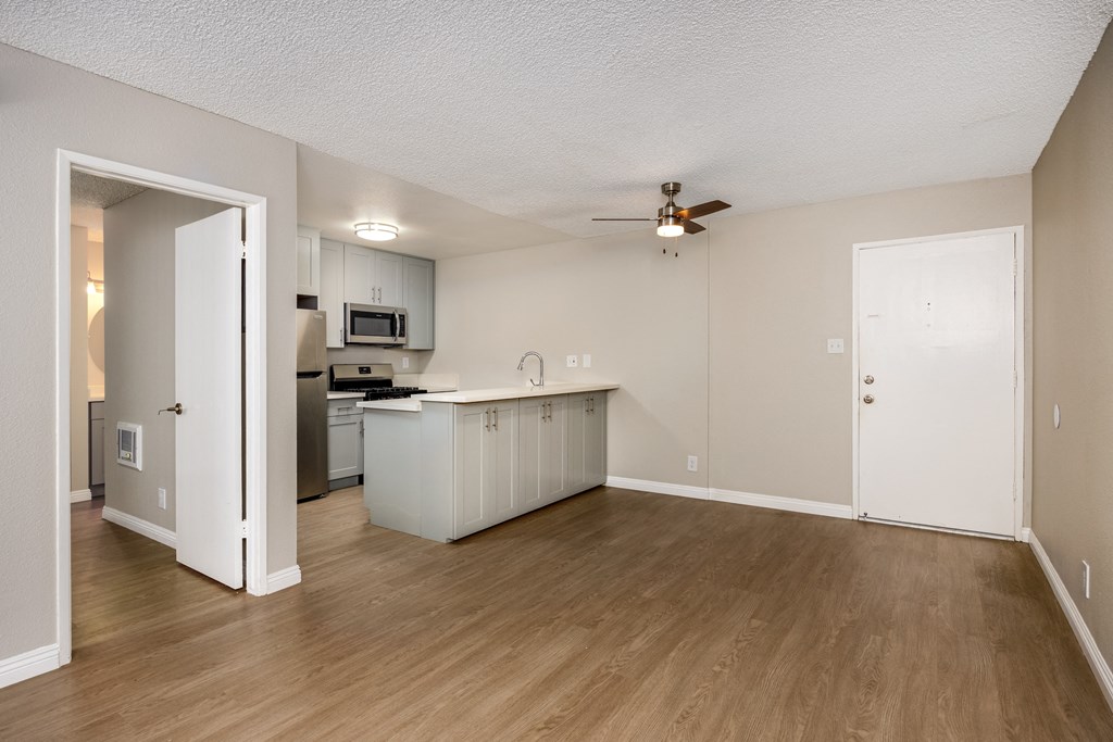 A kitchen with white cabinets and a wooden floor.