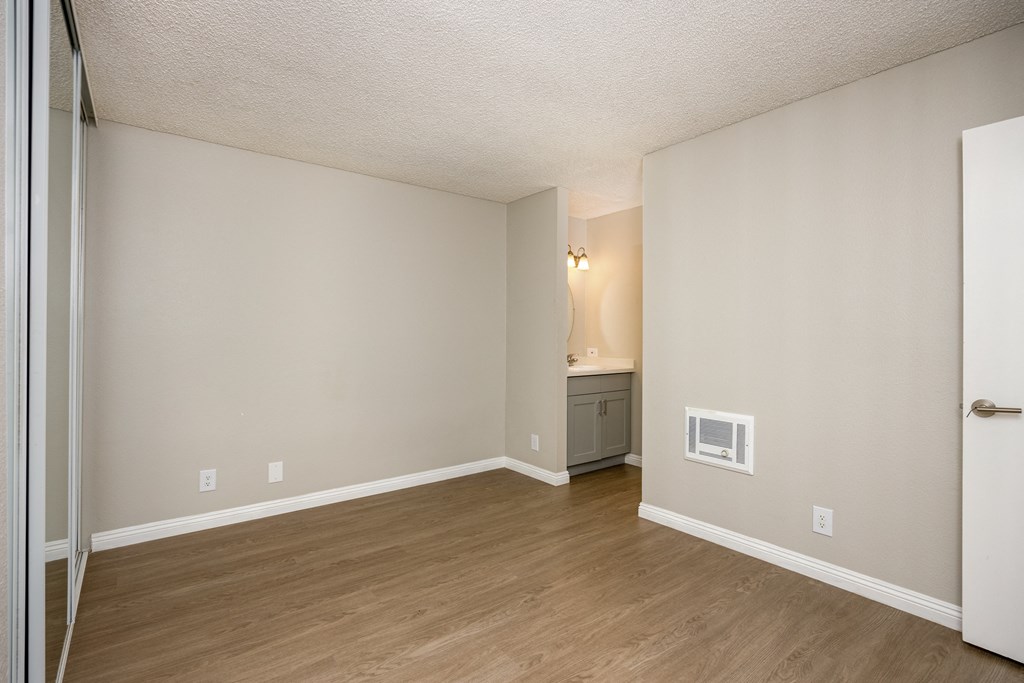 A room with a wooden floor and a small cabinet with a microwave.