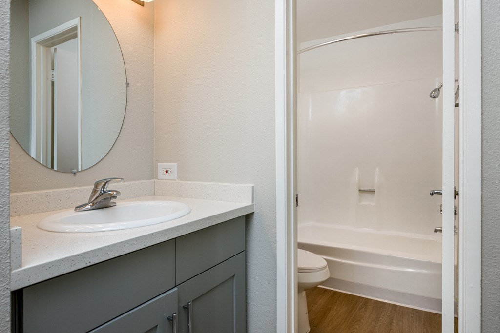 A bathroom with a sink, mirror, and bathtub.