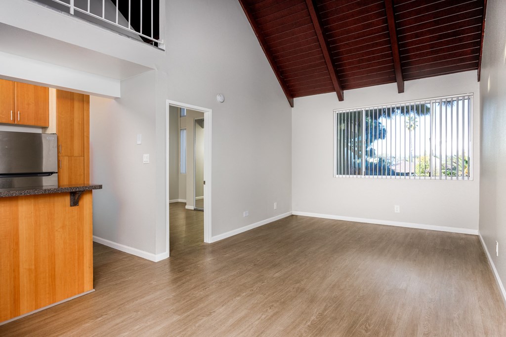 A room with wooden floors and a window with blinds.