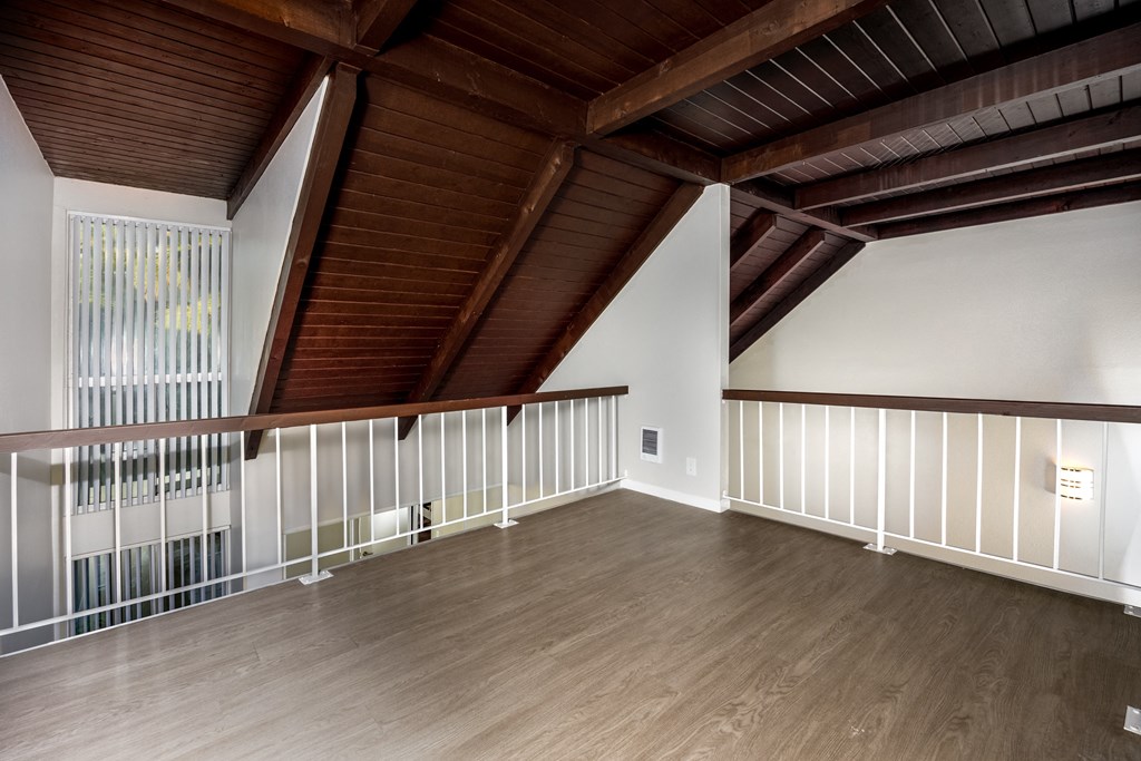 A room with wooden floors and a balcony with white railings.