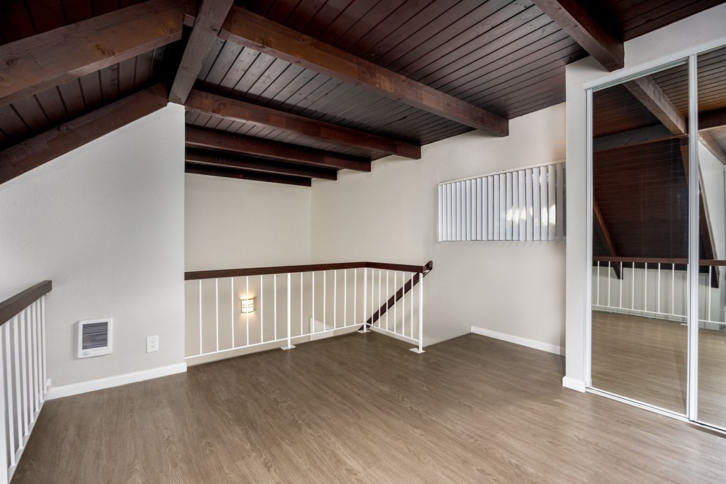 A room with a wooden floor and a staircase with a railing.