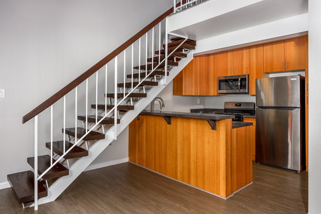 A kitchen with wooden cabinets and a stainless steel refrigerator.