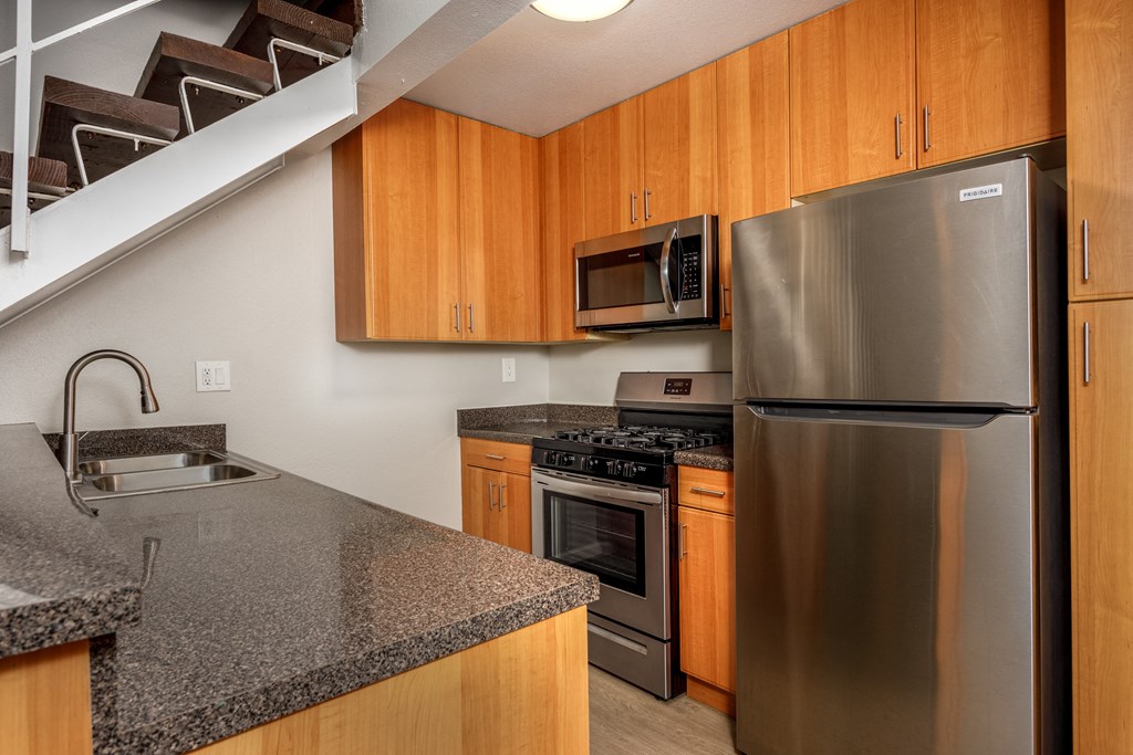 A kitchen with a stainless steel refrigerator and wooden cabinets.