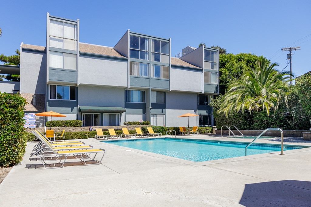 a swimming pool with chairs in front of a building