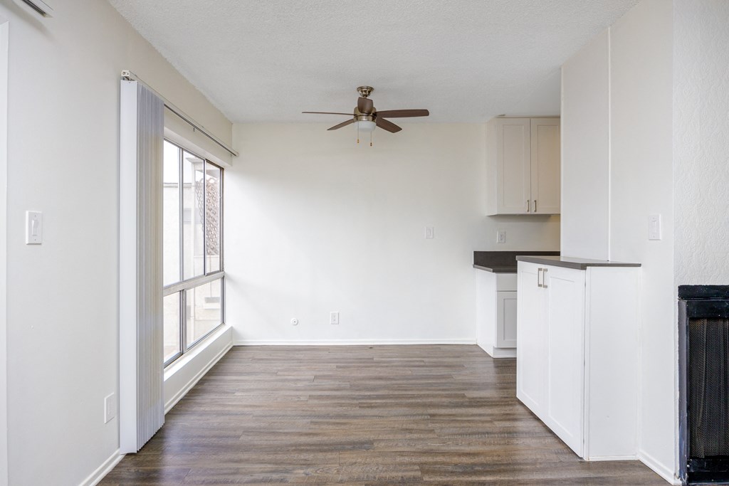 an empty living room with white walls and a ceiling fan