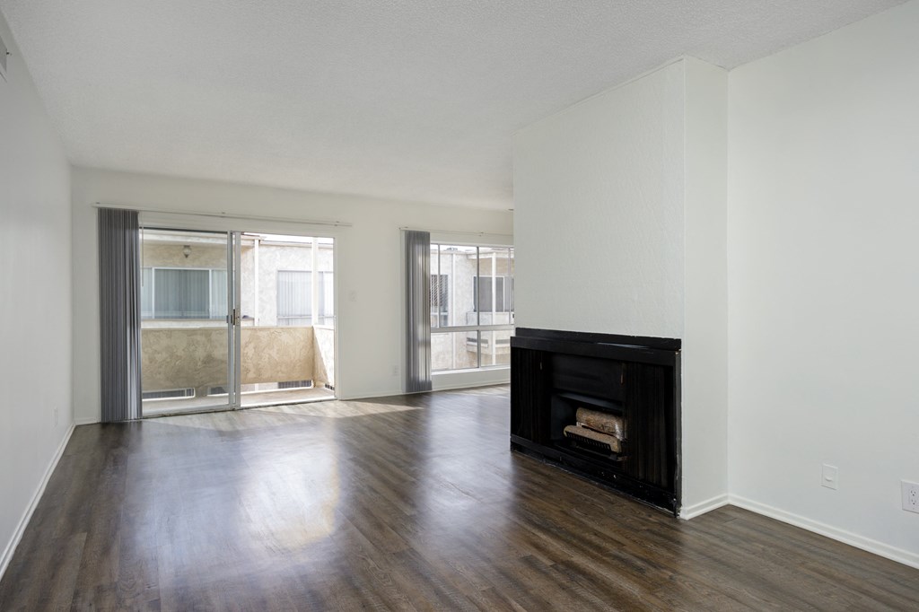an empty living room with a fireplace and wooden floors