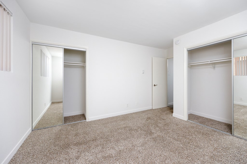 a bedroom with a carpeted floor and two closets