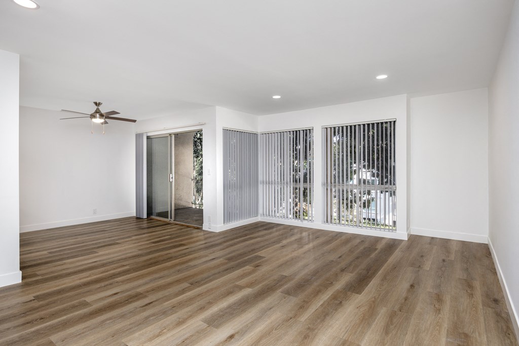 a living room with white walls and wood floors and a sliding glass door