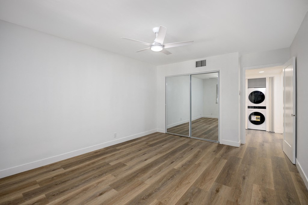 a living room with white walls and wood floors and a mirrored closet