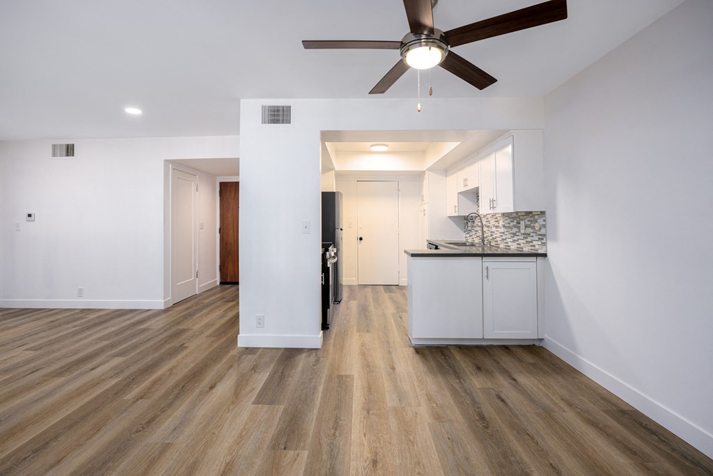 a living room with white walls and a ceiling fan