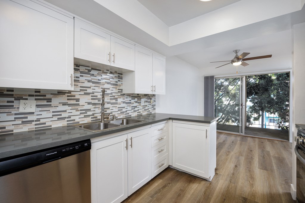 a kitchen with white cabinets and a sink and a window