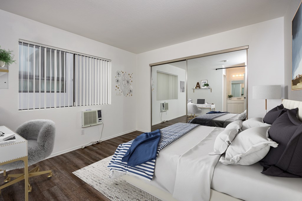 A bedroom with a bed, chair, and mirror.