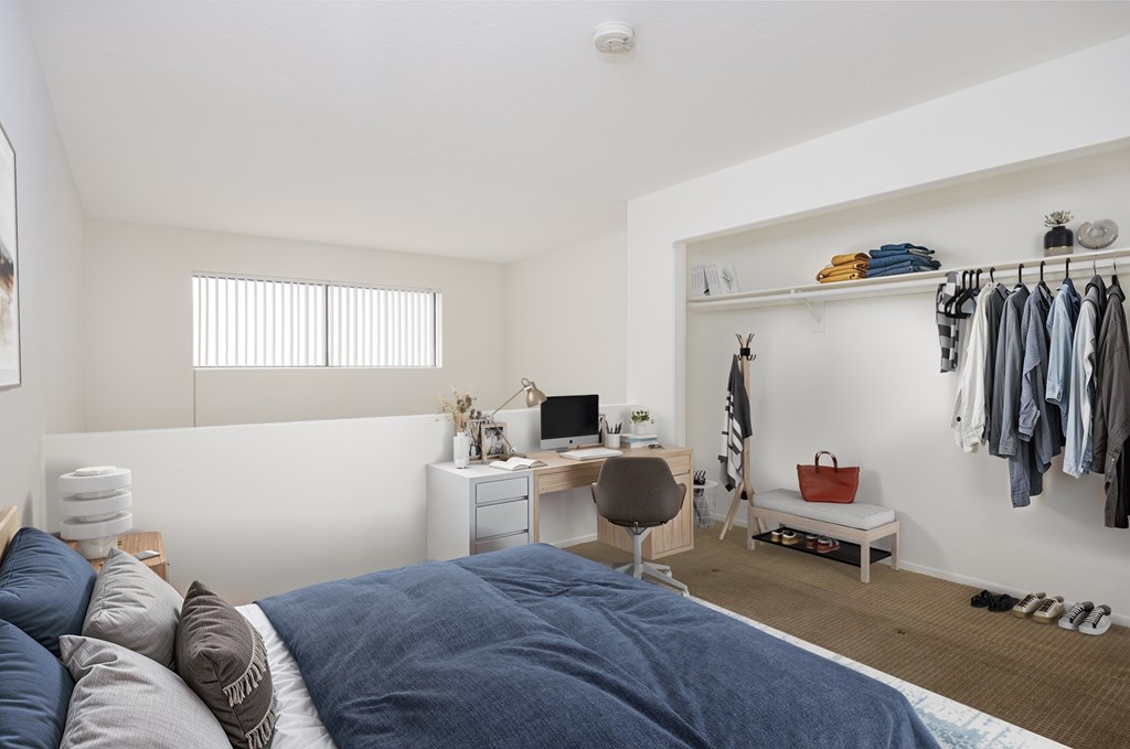 A bedroom with a bed, desk, chair, and closet.