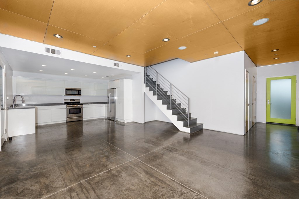 a large room with a staircase and a kitchen in it