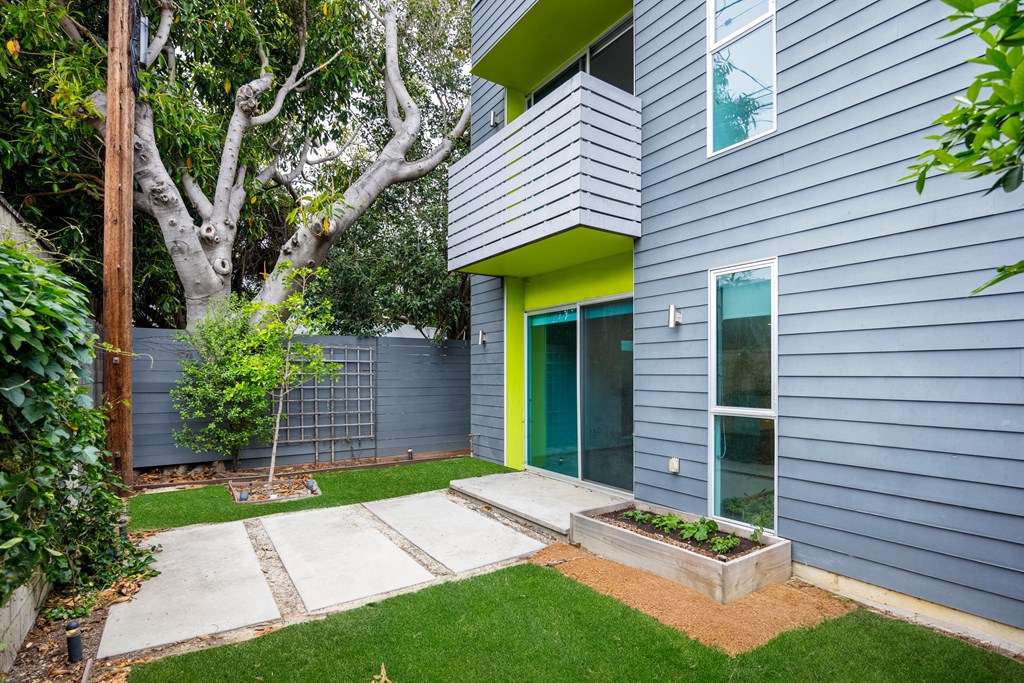 the side of a blue house with a green door and a yard with grass