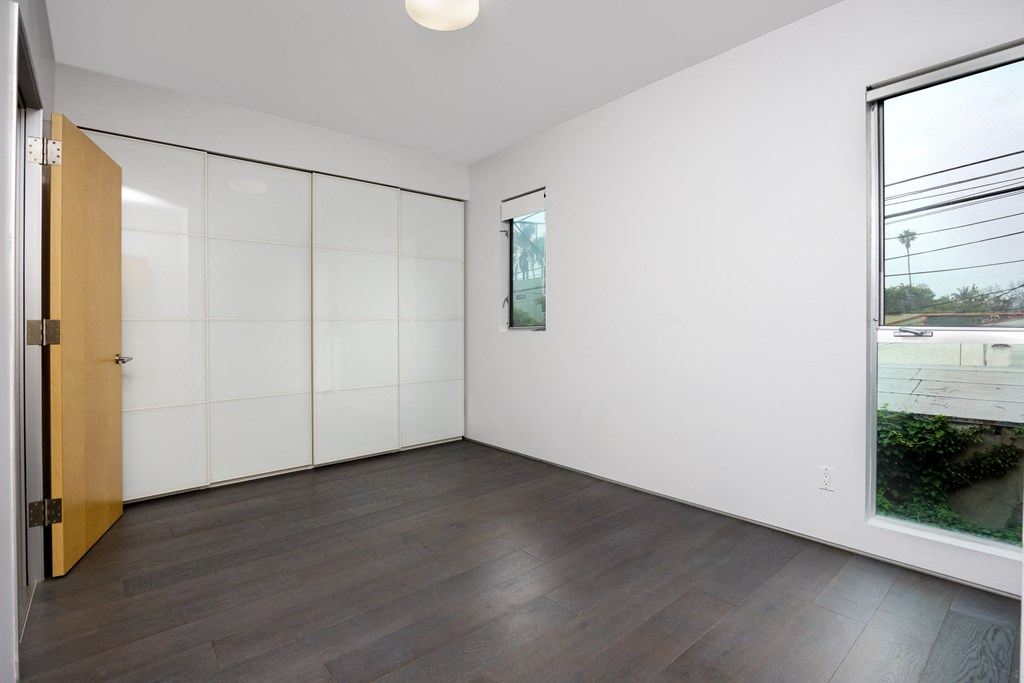 an empty living room with wood floors and white walls and a window