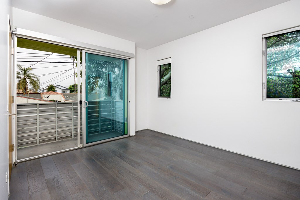 a living room with a door to a balcony and a window and a glass door