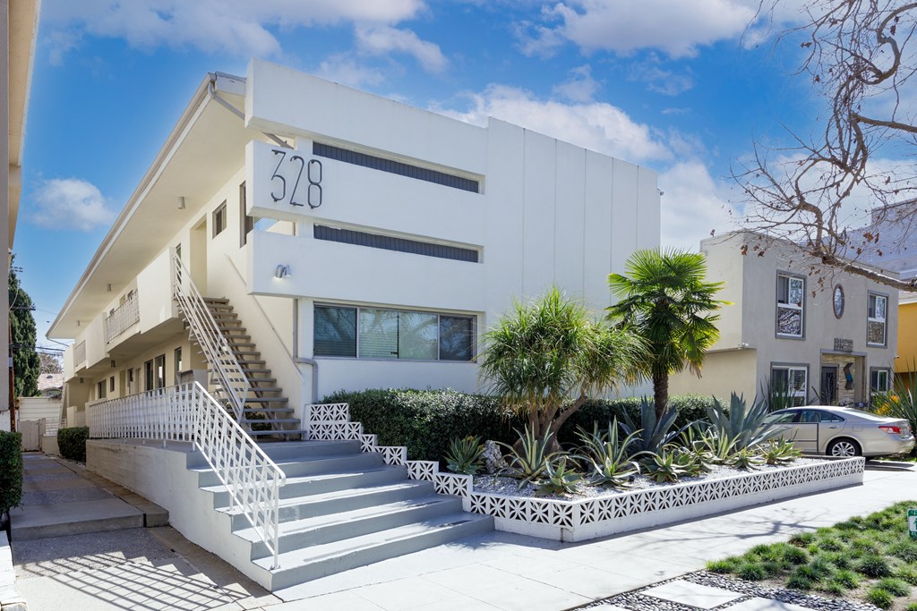 a white building with a staircase and palm trees in front of it