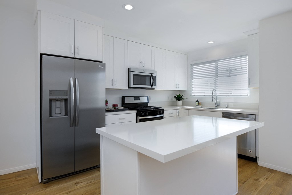 a white kitchen with stainless steel appliances and a large island