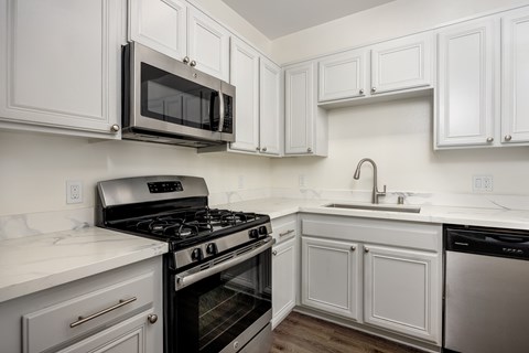 A kitchen with white cabinets and a black stove top oven.
