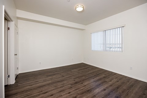 A room with wooden flooring and a window with blinds.