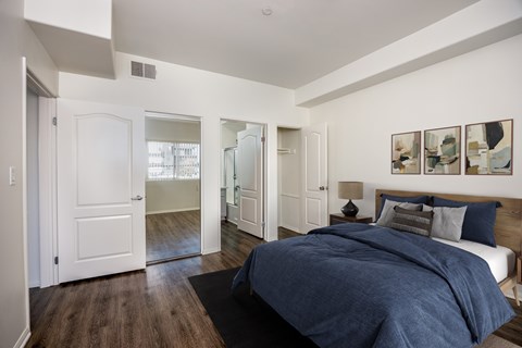 A bedroom with a bed, a nightstand, and a mirror.