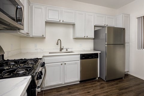 A kitchen with white cabinets and a stainless steel refrigerator.