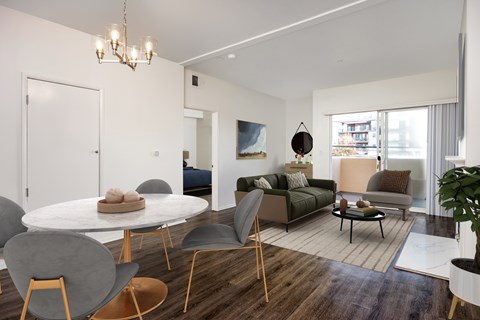 A modern living room with a white table and grey chairs.