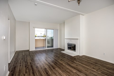 A large, empty room with a fireplace and wooden floors.