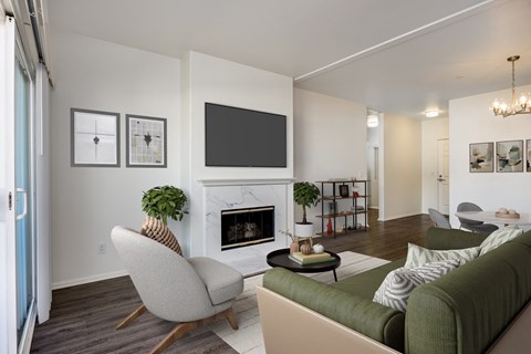 A living room with a green couch, a fireplace, and a television.