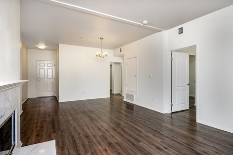 A large empty room with wood floors and white walls.