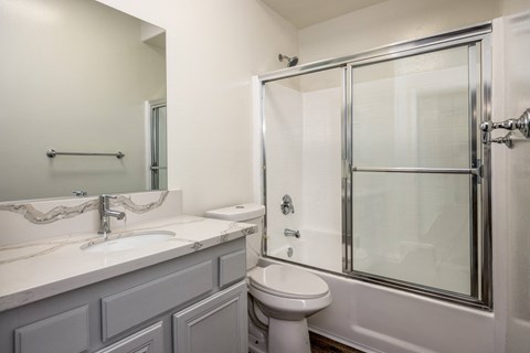 A white bathroom with a toilet, sink, and shower.