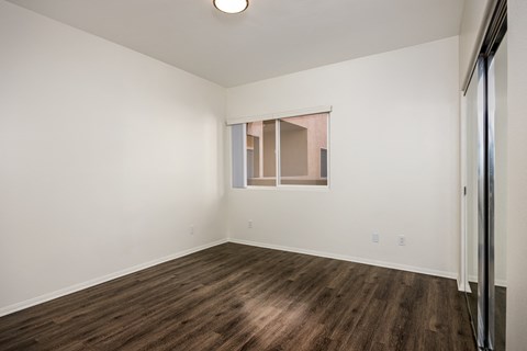 A room with wooden flooring and a window with blinds.