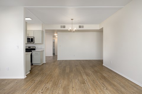 an empty living room and kitchen with white walls and wood flooring